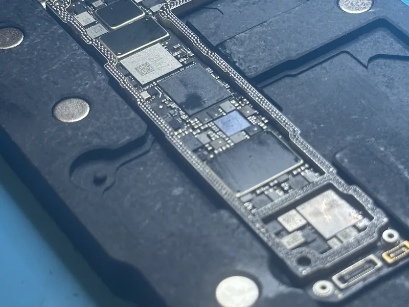 Phone board in the repair fixture, with the shields and bottom connector exposed